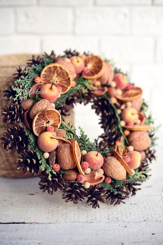 a fall to winter wreath with evergreens, pinecones, nuts, faux apples and berries is a lovely idea