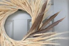a fall wheat wreath with feathers is a bold and chic fall decoration on your front door