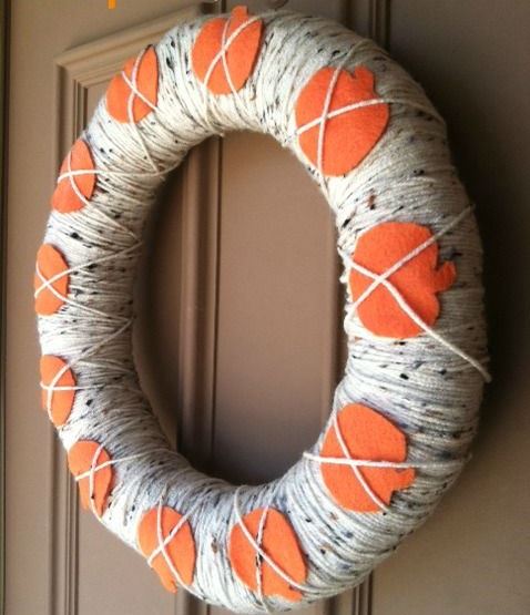 a fall wreath covered with black and white yarn and orange fabric pumpkins is a fun and easy idea