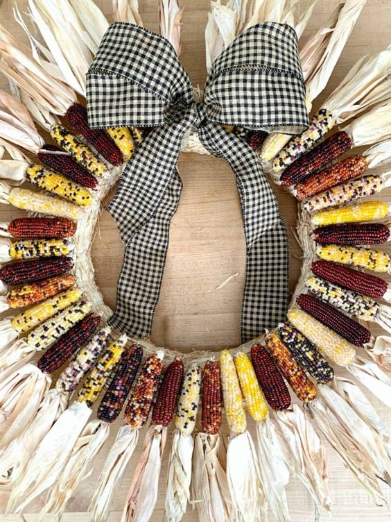 a fall wreath made of Indian corn cobs with husks and topped with a cool gingham bow is a fantastic idea for the fall