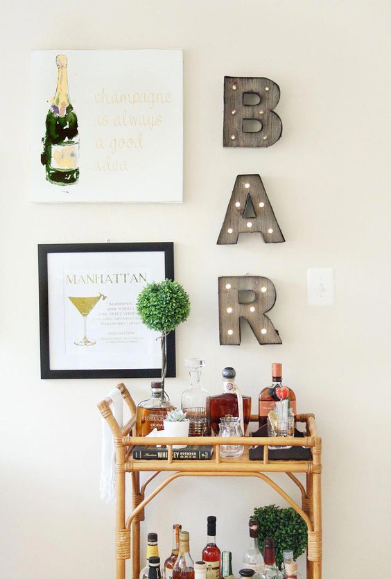 a fun and modern bar space with artworks, a marquee light, a bamboo cart and some potted greenery is very cool