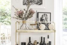 a gold bar cart with artworks, blooms and greenery is a cool idea for a modern space