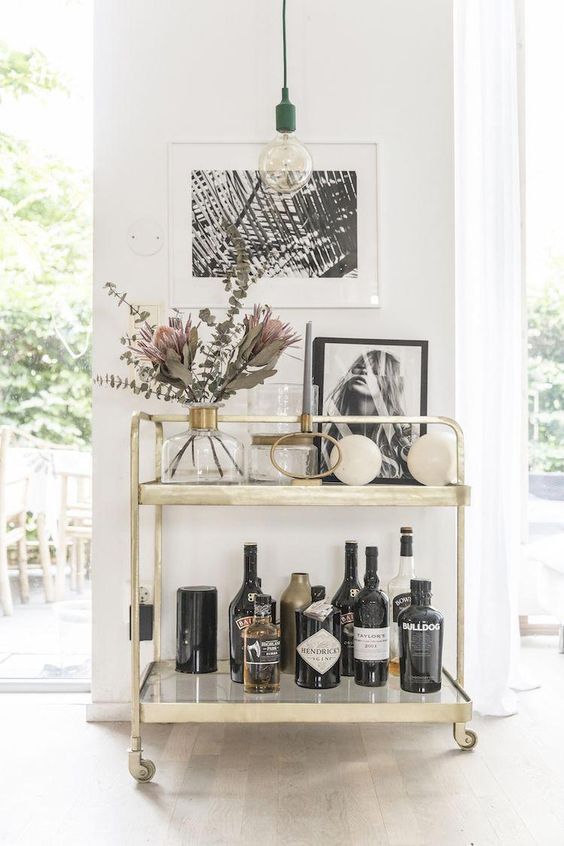 a gold bar cart with artworks, blooms and greenery is a cool idea for a modern space