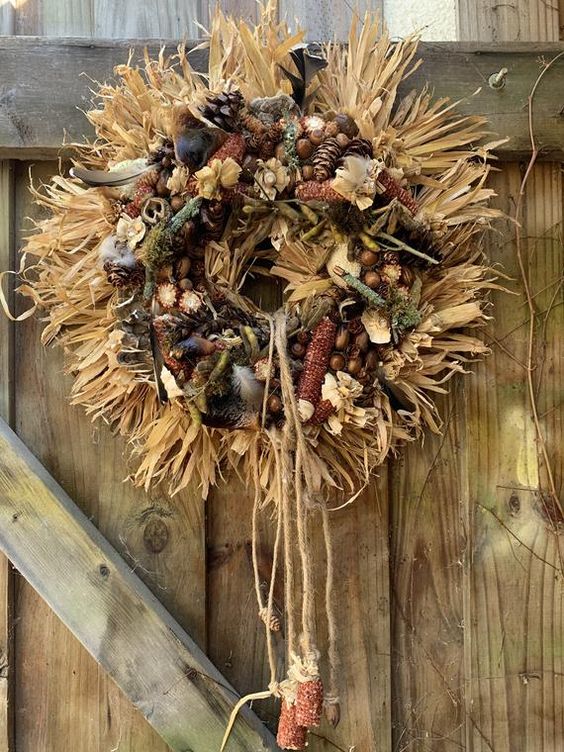 a messy fall wreath of corn husks, corn cobs, berries, acorns, pinecones and twine is a lovely and bold idea for woodland outdoor decor