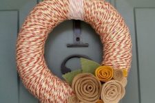 a moody fall wreath with red and white yarn, neutral fabric flowers and leaves is a cool idea for decorating