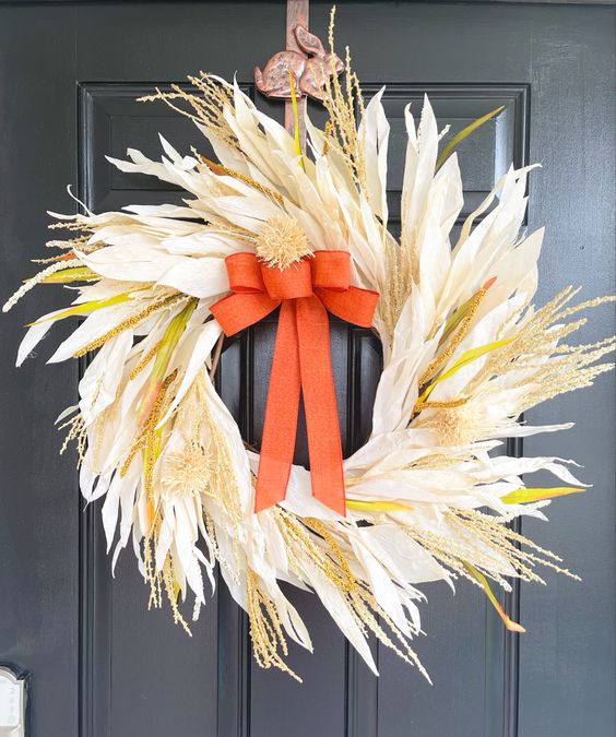 a neutral corn husk wreath with wheat, yellow touches, an orange burlap bow will add a bit of color and a lot of texture to the space