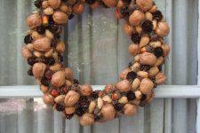 a pretty woodland fall wreath with glossy nuts, acorns, pinecones, little pumpkins and hay can be easily DIYed