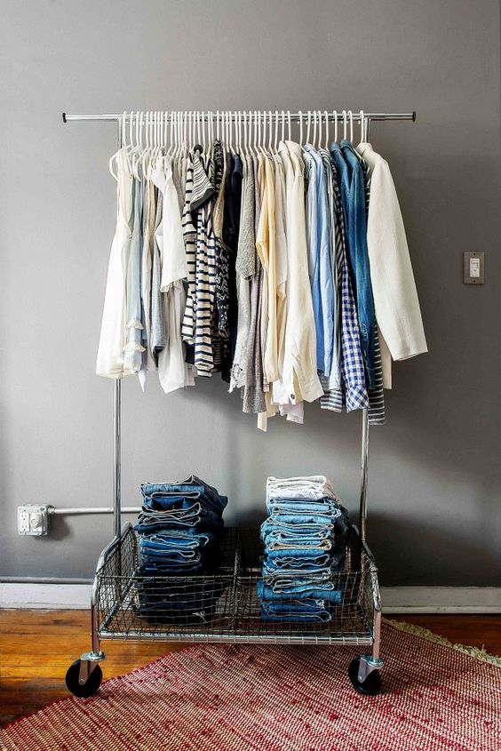 a simple metal clothes rack on casters with lots of hangers and compartments for storage in the lower part