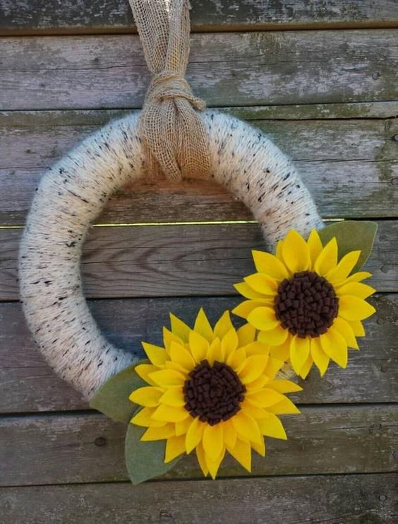 a simple summer to fall wreath covered with neutral yarn and with faux sunflowers of fabric and leaves