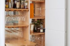 a small built-in home bar with a mirror backsplash, a drawer and shelves is a cool idea to save some space
