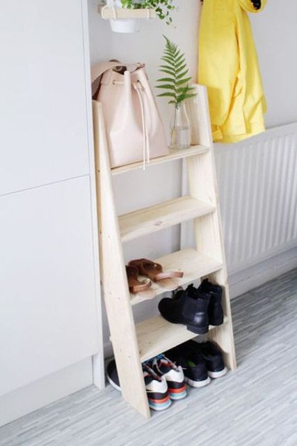 een kleine houten ladder gebruikt als een plank voor schoenen en tassen is een simpel idee voor een slaapkamer of hal