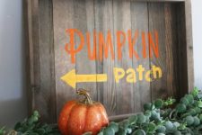a stained fall sign with colorful letters, fresh greenery and colorful faux pumpkins