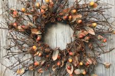 a twig fall wreath with acorns, berries, faux leaves and pinecones looks and feels very fall-like