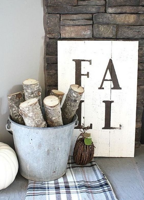 a very simple monochromatic fall sign and a bucket with cut branches and a plaid blanket for fall decor