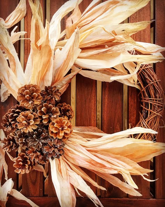 a vine wreath with oversized corn husks and pinecones on one side is a fantastic idea for a rustic space