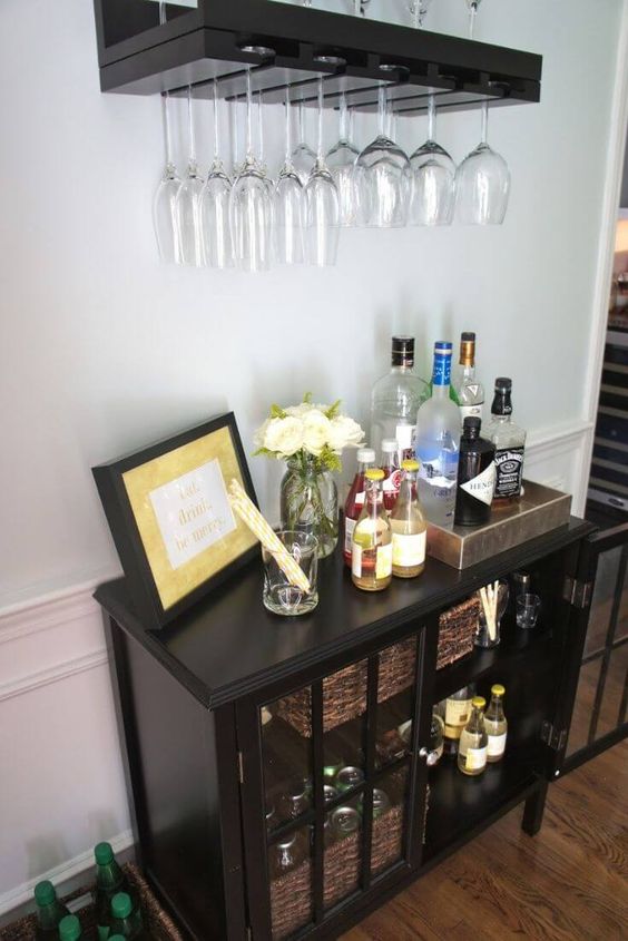 a vintage bar space with a dark open shelf, a dark glass cabinet and some blooms and an artwork is elegant