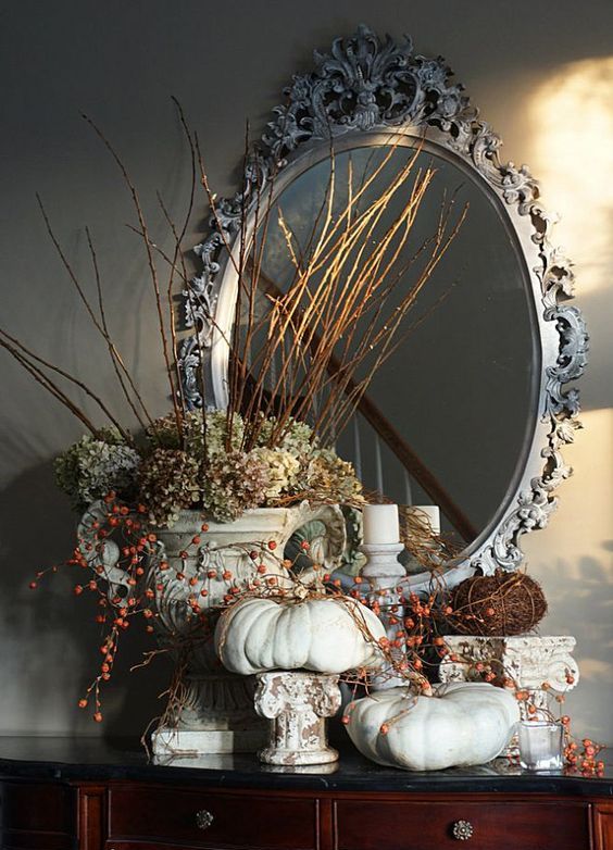 a vintage rustic decoration with lots of neutral pumpkins with berries, green hydrangeas and twigs and sticks