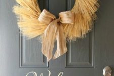 a wheath wreath with a burlap bow is a cool decoration for decorating your front door in fall style
