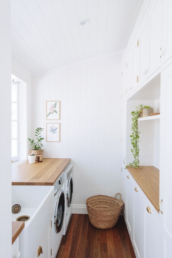 a white farmhouse laundry with shiplap walls and shaker style cabinets, a large sink and cool appliances plus a basket