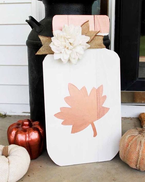 a white mason jar with leaf fall sign with a burlap ribbon and a faux white flower for the fall