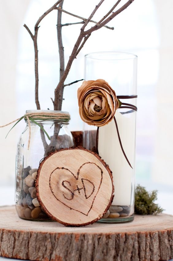 a wood slice with a wood burnt heart, a candle on pebbles, a jar with pebbles, moss and branches or twigs