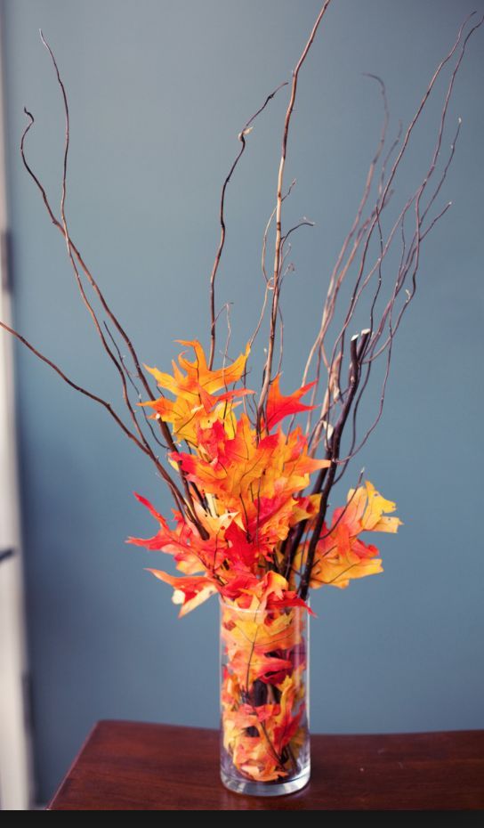 an easy and budget-friendly fall centerpiece of twigs and bright faux leaves in a vase to make last minute