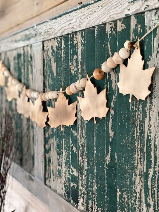 such a natural fall garland can be made of wooden beads and leaves, and it looks cozy and stylish in fall and Thanksgiving spaces