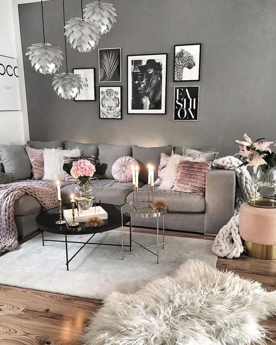 a Scandi living room with a grey wall and a grey sofa, pink pillows and blankets, catchy scallop pendant lamps