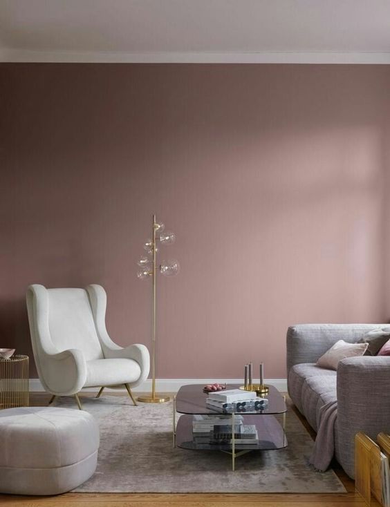 a beautiful mauve living room with a grey sofa, a creamy chair and a pouf, a grey rug and a two-tiered coffee table