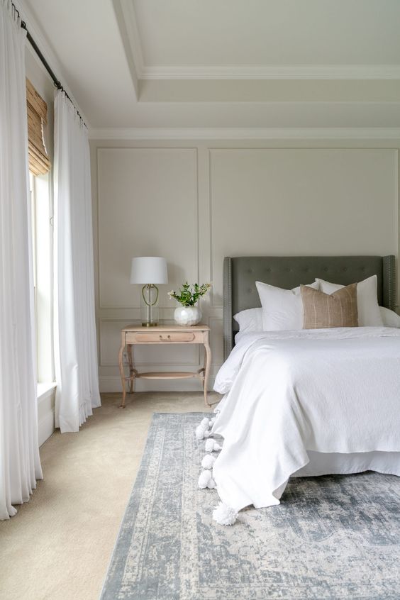 a beautiful neutral bedroom with tan molded walls, a green bed, neutral textiles and a blue crushed velvet rug is a relaxed space