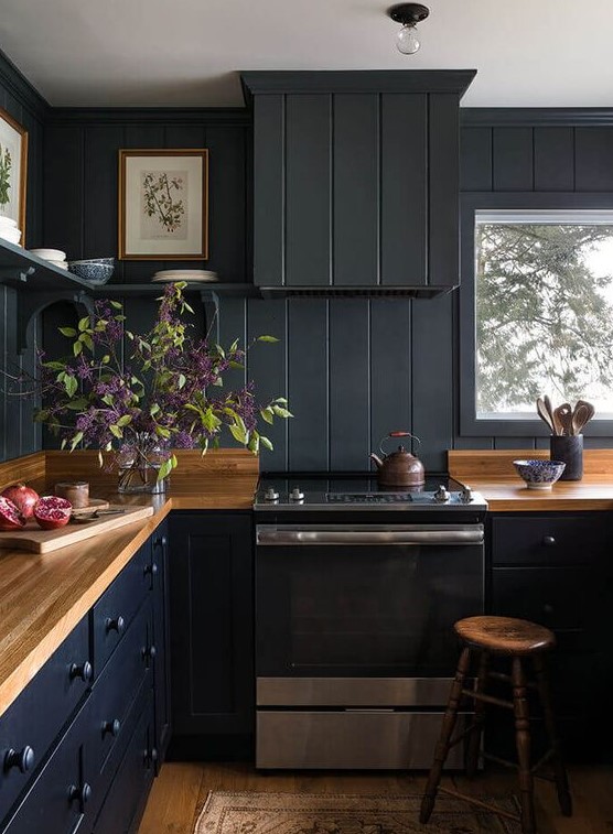 a black farmhouse kitchen done with beadboard, light-colored wooden countertops and stools plus open shelving