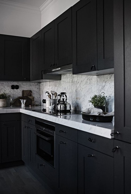 a black framhouse kitchen with white marble countertops and a backsplash is a chic and stylish idea