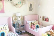 a bright shared girls’ bedroom with pink IKEA Sundvik beds, faux animal heads, bright toys and banners