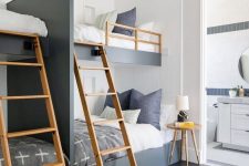 a catchy and contrasting graphite grey and white kids’ room with four built-in bunk beds, wooden ladders and a side table, a wooden pendant lamp