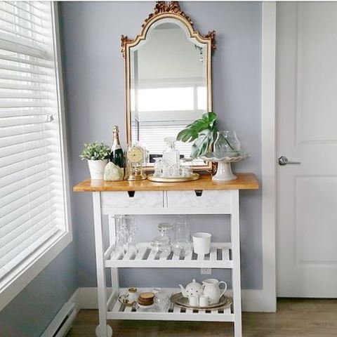 a chic IKEA Forhoja cart done with marble contact paper, with a wooden countertop as a small home bar