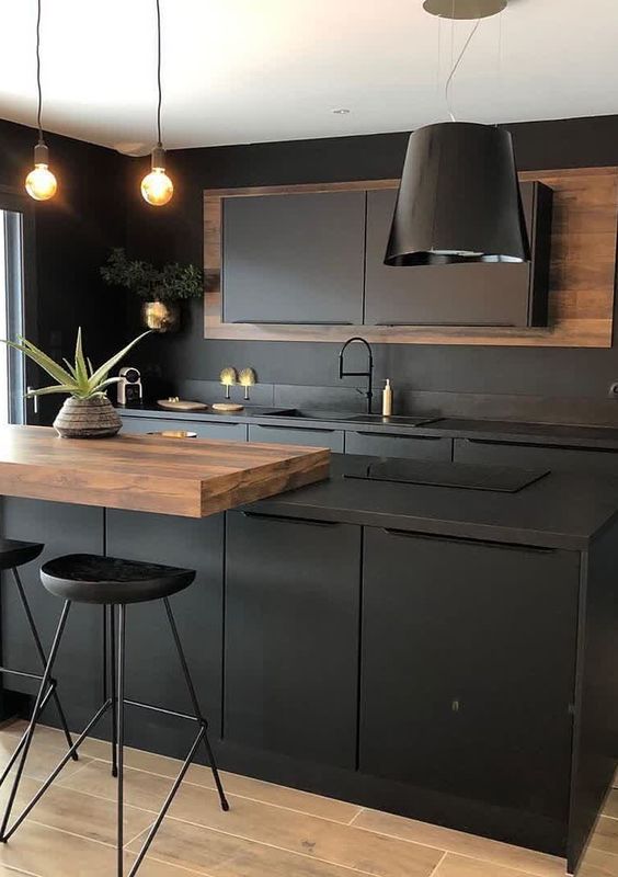 a chic matte black kitchen with metal cabinets and a kitchen island, a rich-stained countertop, a black pendant lamp and stools