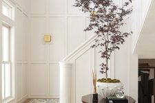 a chic neutral entryway with molding, with light-stained floor, a large and catchy plant for a statement is amazing