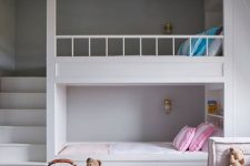a clean minimal kids’ room with built-in bunk beds, bright bedding and a rug, a low seat sofa by the window, baskets for storage and built-in lights