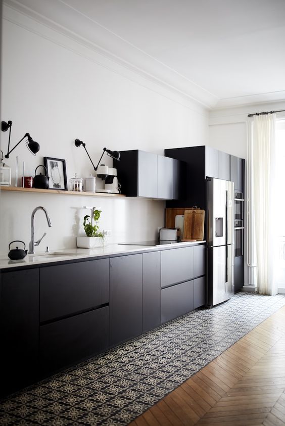 a cool Scandinavian kitchen with matte black cabinets, white countertops and a backsplash, an open shelf and black and white tiles on the floor