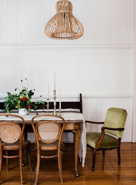 a country style dining room with a vintage stained table, some matching chairs, an antique green chair and a black bench