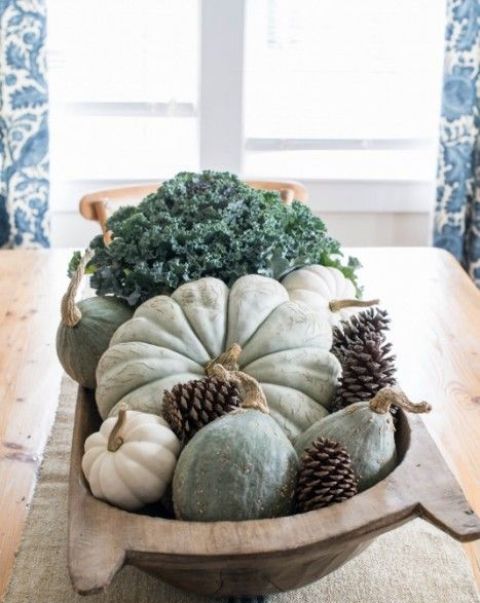 a cozy harvest centerpiece of a dough bowl with hirloom pumpkins and gourds, pinecones and fresh veggies