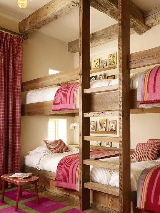 a cozy rustic kids' room with four built-in bunk beds, with a ladder and pink and white bedding, with matching curtains and a rug