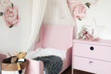 a delicate girl’s bedroom with handpainted florals, a pink Sundvik bed, a printed rug, a canopy and a storage bag
