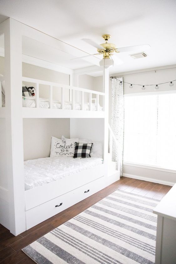 a dove grey kids' room with a built-in bunk bed and neutral bedding, a striped rug and lights and lamps is a welcoming space