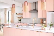 a feminine glam kitchen with pink cabinets, a grey backsplash and white countertops, dusty pink pendant lamps with fringe