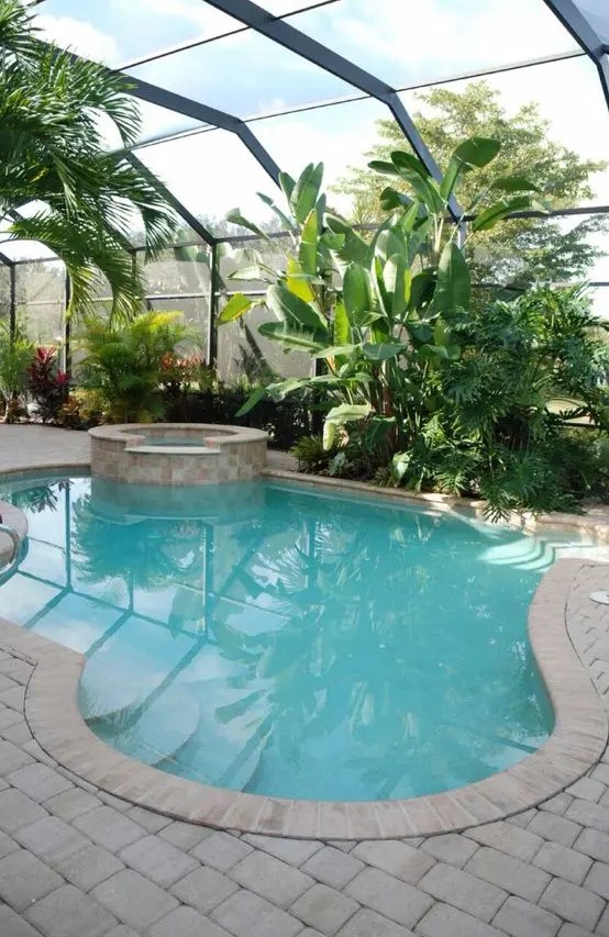 a glazed orangery with lots of greenery and blooms and a uniquely shaped pool with a hot tub is a lovely space to spend time