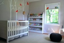 a laconic nursery with painted trees on the wall, a bookshelf, a Sundvik crib and a black crochet pouf