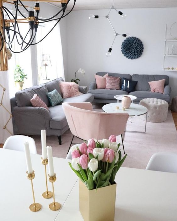 a light-filled Scandi living room with grey sofas, pink pillows and a chair, a couple of coffee tables
