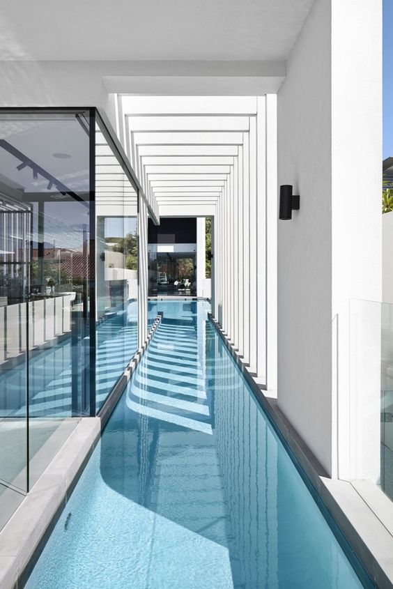 a long and narrow pool built inside a minimalist house is a stylish and cool idea to swim in all weathers