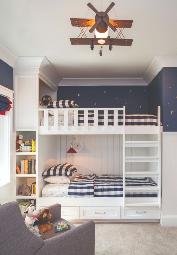 a lovely shared kids' room with starry night wallpaper, a white built-in bunk bed, built-in shelves and a chair plus lots of toys